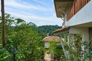 A building with a balcony overlooking a garden with various plants and flowers. - The Divine Villa (Heenatigala)