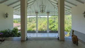 A covered outdoor area with a view of greenery, columns, and hanging lanterns. - The Divine Villa (Heenatigala)