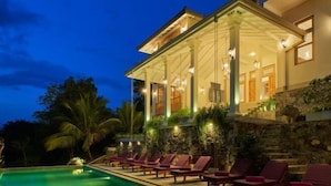 A luxurious villa with a swimming pool, outdoor seating, and a well-lit entrance. - The Divine Villa (Heenatigala)