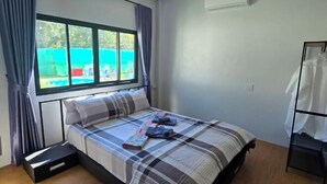 Une chambre à coucher comprenant un lit, une fenêtre, une table de chevet et un portant à vêtements.
