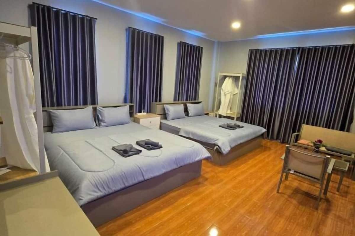 Une chambre d’hôtel avec deux lits, un bureau et une chaise.