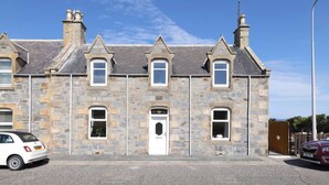A stone building with a symmetrical facade, multiple windows, and a central door.