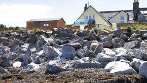 A rocky landscape with a house in the background.