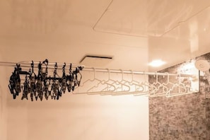 A wall-mounted drying rack with multiple hangers and a ceiling vent. - THE SKY (Sapporo)