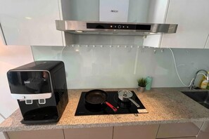 A modern kitchen with a coffee machine, a stove, and a small potted plant. - M9 Prime Suite@H20 Medalla CittaMall SubangAirport (Petaling Jaya)