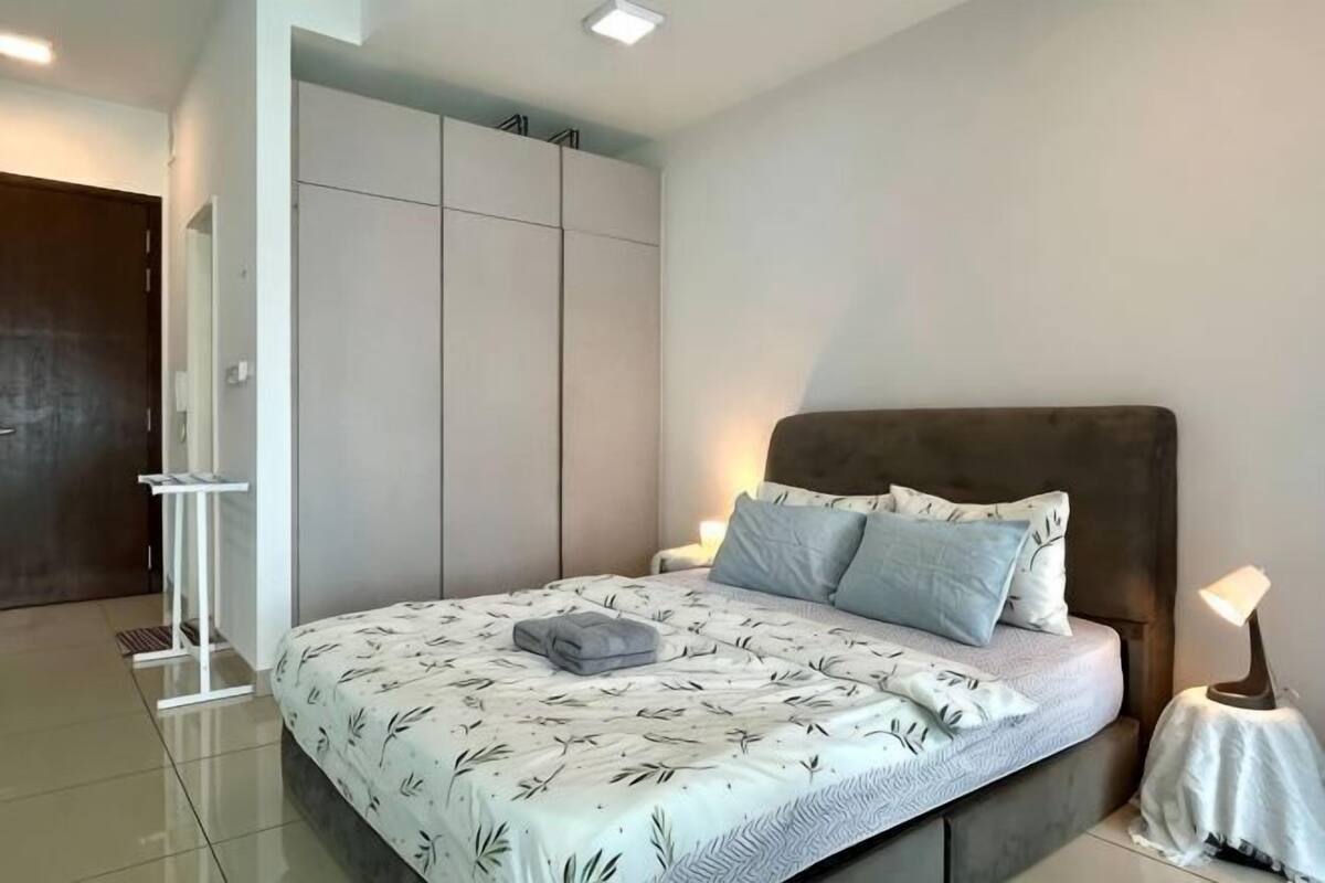A bedroom with a bed, bedside tables, a wardrobe, and a door.