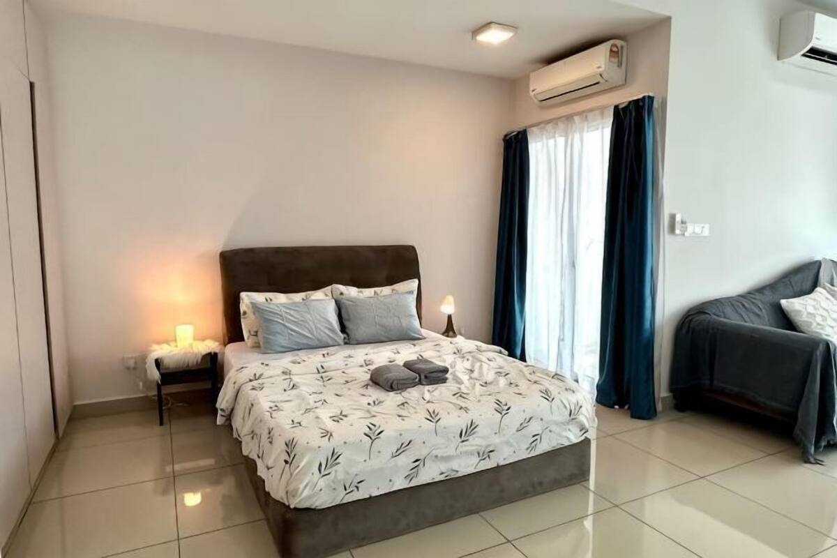 A bedroom with a bed, bedside table, and a window with curtains.