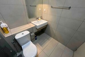 A bathroom with a toilet, sink, and mirror. - M9 Prime Suite@H20 Medalla CittaMall SubangAirport (Petaling Jaya)