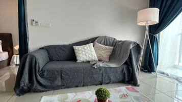 A modern living room with a grey sofa, a small table with a potted plant, and a floor lamp.