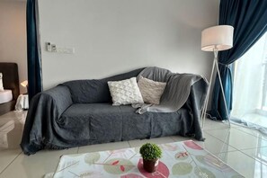 Egy modern nappali, szürke színű kanapéval, egy kis asztallal, melyen egy virágtál található, és egy állólámpával.