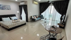 A modern living room with a bed, a sofa, a dining table with chairs, and large windows with curtains. - M9 Prime Suite@H20 Medalla CittaMall SubangAirport (Petaling Jaya)