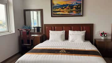 Une chambre d’hôtel avec un lit, une table de chevet, un miroir, une fenêtre et un tableau au mur.