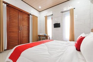 Une chambre d’hôtel avec un lit, une armoire en bois et une petite table avec une chaise.