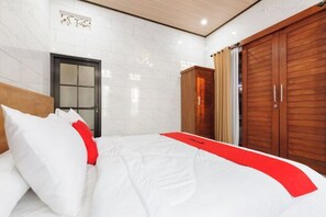 Une chambre d’hôtel avec un lit, une armoire en bois et une porte.