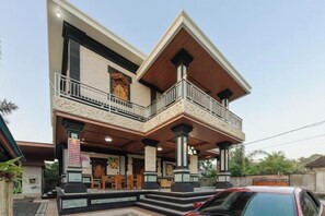 A two-story house with a balcony, a front porch, and a car parked in front. - RedDoorz @ Pondok Kampung Harmony Ubud (Bali)