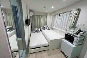 A compact hotel room with a single bed, a small kitchenette, and a mirror. - MTOKYO (Tokyo)
