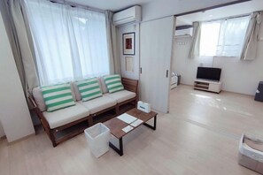 A modern living room with a sofa, a coffee table, a TV, and a wardrobe. - MTOKYO (Tokyo)