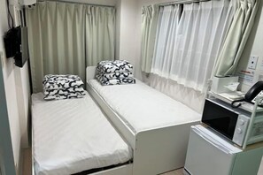A small, single-bed room with a microwave and a small cabinet. - MTOKYO (Tokyo)