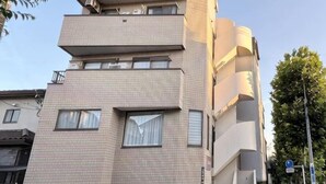 A multi-story building with a flat facade, large windows, and a visible staircase leading to the entrance. - MTOKYO (Tokyo)
