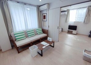 A modern living room with a sofa, a TV, and a trash bin. - MTOKYO (Tokyo)