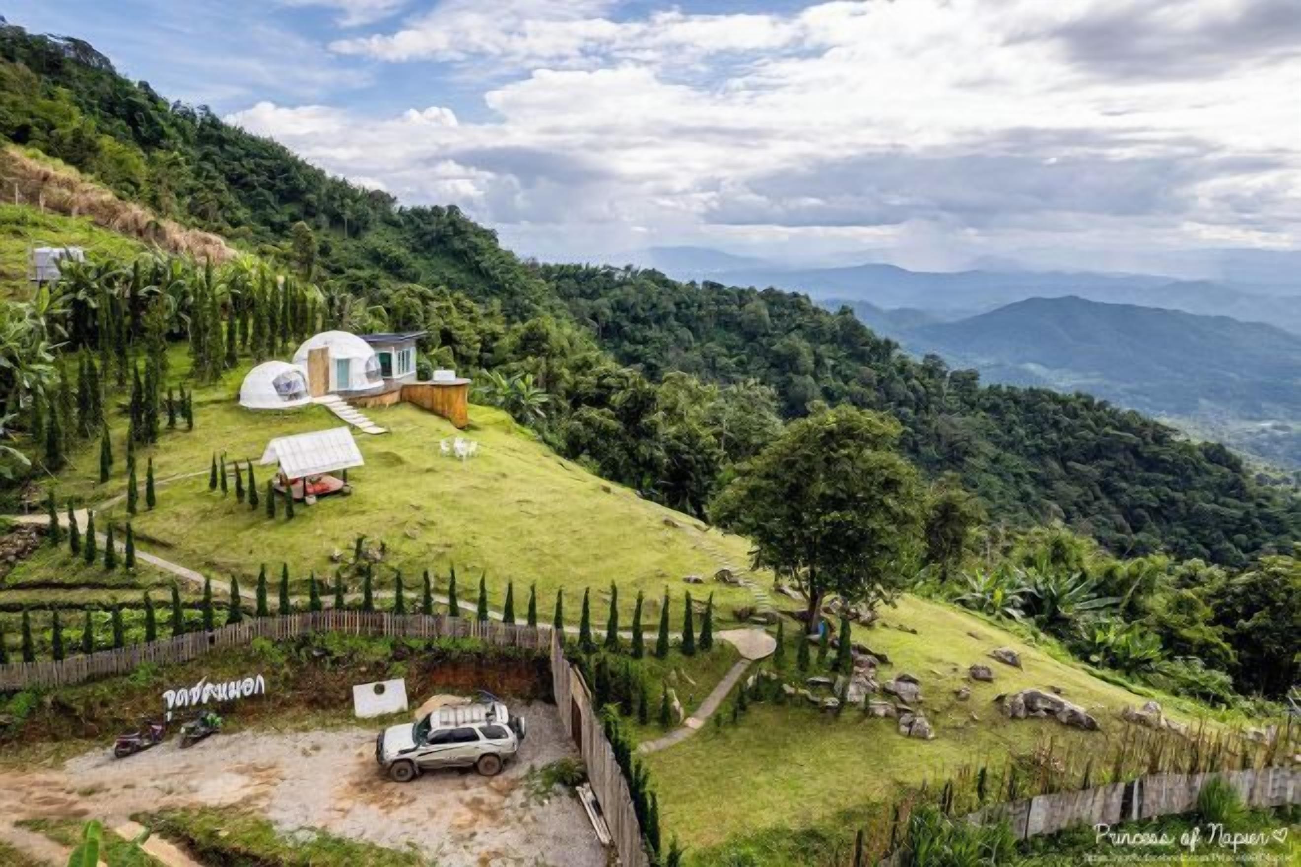 Propiedad aislada y elevada con una casa pequeña, un coche para invitados y un jardín vallado.