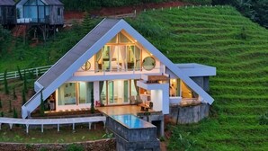 A modern house with a large glass facade, a swimming pool, and a stone retaining wall. - Thenor (Samoeng)