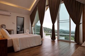 Une chambre avec un grand lit, une table de chevet, un miroir et une vue dégagée grâce à de grandes fenêtres du sol au plafond.
