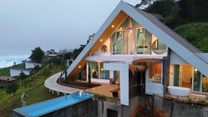 A modern house with a large glass facade, a swimming pool, and a thatched roof. - Thenor (Samoeng)