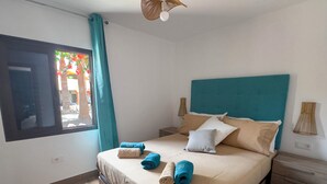 Una habitación de hotel con una cama, una mesita de noche, una lámpara y una ventana con cortinas.