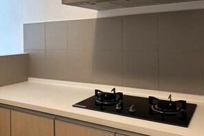 Una cocina con dos estufas a gas negras, una encimera blanca y salpicadero de azulejos color crema.