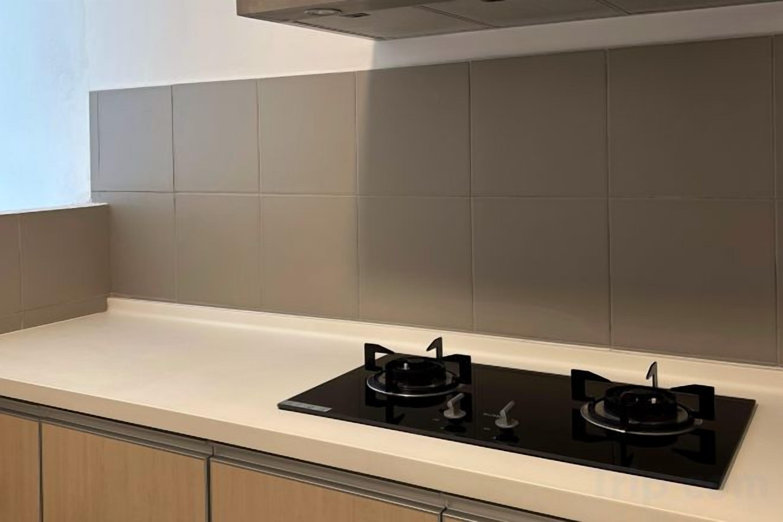 A kitchen with a white countertop, two black stovetops, and grey tiled backsplash.