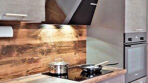 Una cocina moderna con protector de salpicadero de madera, electrodomésticos de acero inoxidable y horno empotrado.