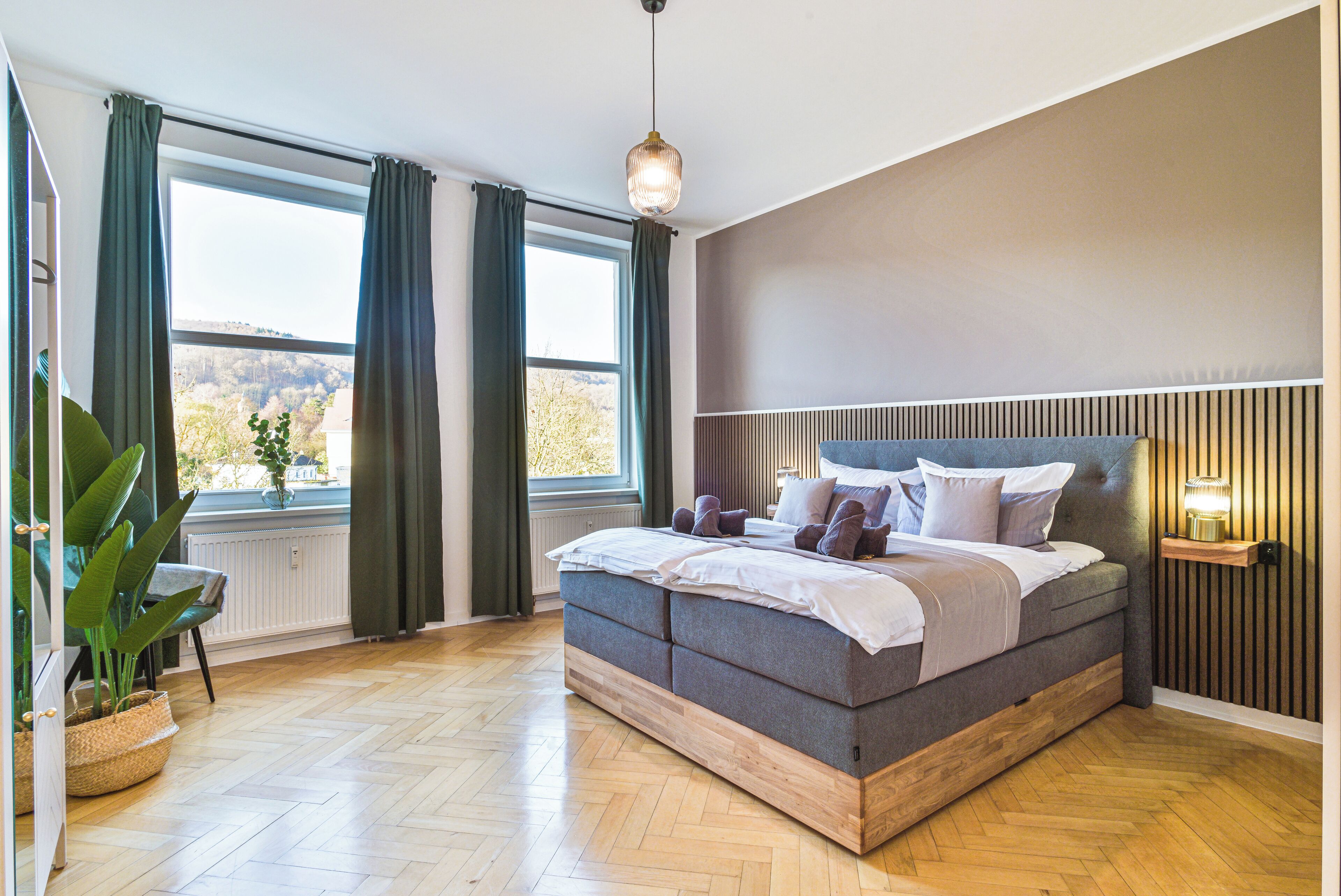 Une chambre moderne avec un grand lit, une vue sur l’extérieur et une table de chevet avec une lampe.