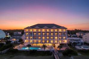 Ett hotell med flera våningar och ett poolområde, omgivet av andra byggnader.