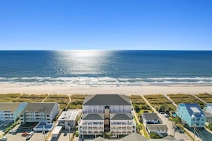 A coastal hotel with multiple buildings, a beach view, and a parking area.