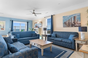 A living room with two blue sofas, a wooden coffee table, and a ceiling fan.