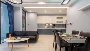 A modern living space with a dining area, a sofa, and a kitchen in the background. - Vinhome Metropolis Luxury Apartment - Tiramisu House (Hanoi)