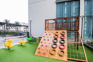 Un espace de jeux pour enfants avec une structure d’escalade et un mur d’escalade fait de pneus.
