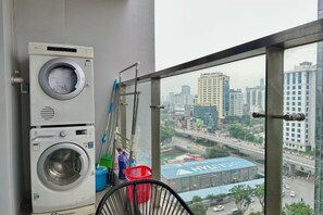 Un espace dédié à la buanderie, avec des machines à laver superposées, une serpillière et un panier rouge.