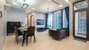 A modern living room with a dining area, a TV, and a large window with curtains. - Vinhome Metropolis Luxury Apartment - Tiramisu House (Hanoi)