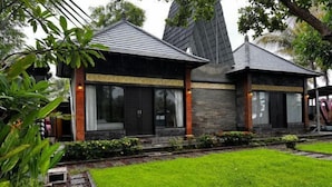 A modern building with a stone facade, large windows, and a well-maintained lawn.