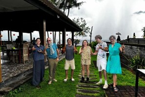 A group of people standing on a grassy area with a covered structure in the background. - Cik Bunk Beach Front Homestay near Tulamben Bali (Bali)