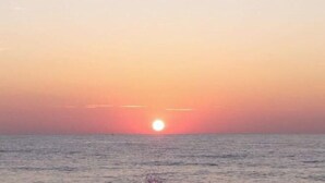 A sunset over the ocean with a clear sky.