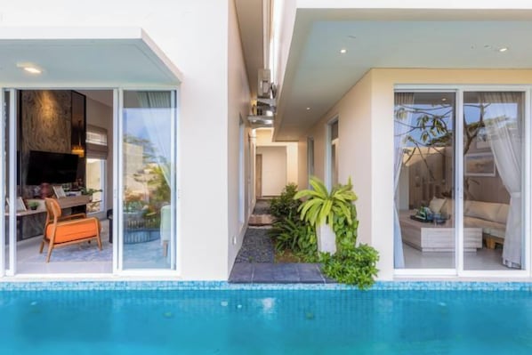 Une maison moderne dotée d’une piscine, d’un coin repas et d’une chambre avec une grande fenêtre.