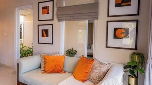 Ein modernes Wohnzimmer mit einem hellblauen Sofa, orangefarbenen Kissen und gerahmten Kunstwerken an den Wänden.