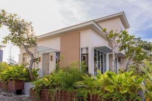 Une maison moderne à deux étages, dotée d’un toit plat, de grandes fenêtres et d’un porche couvert.