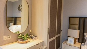Ein Hotelzimmer mit Bett, Nachttisch, Lampe und Spiegel.