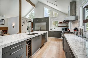 A modern kitchen with a marble countertop, stainless steel appliances, and a wooden floor.