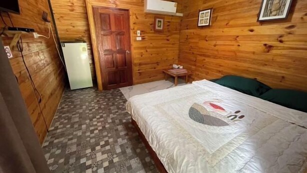 A wooden-paneled room with a bed, a small table, and a door. - IUnn Resort (Rayong)