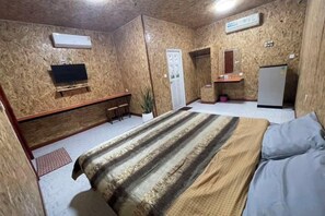 A room with a bed, a desk, a chair, a TV, and a refrigerator.